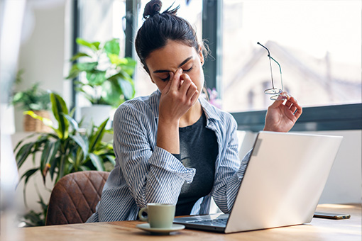 Woman with eye strain looking at laptop