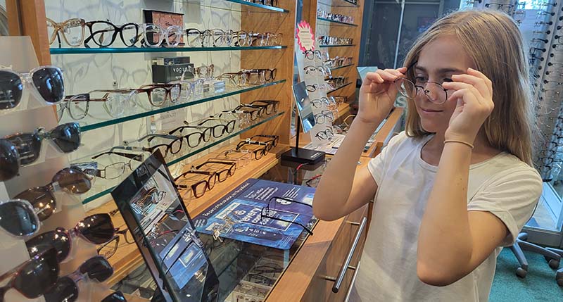 young girl trying on glasses in clinic